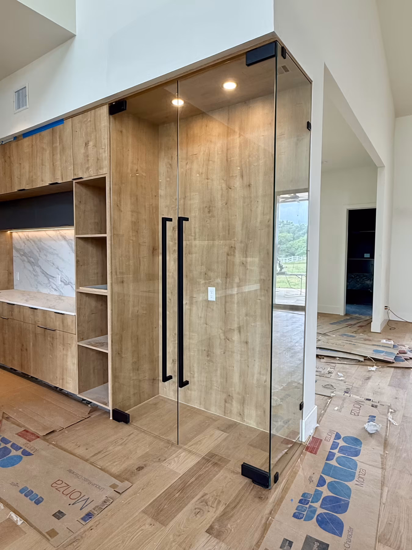 Frameless glass wine room enclosure with black hardware and wood cabinetry